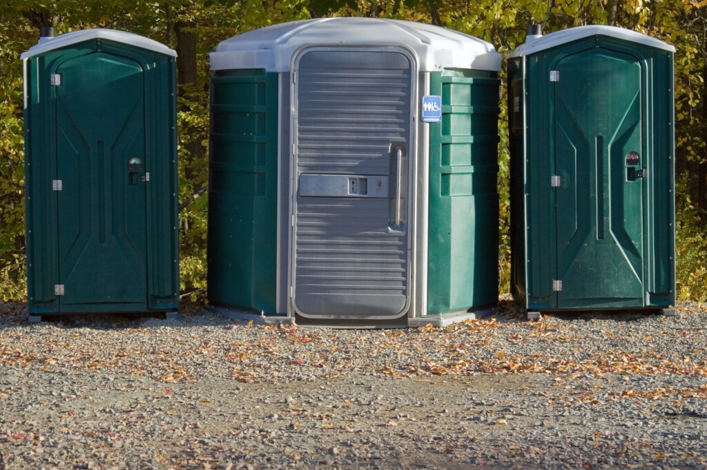 three green portable toilets